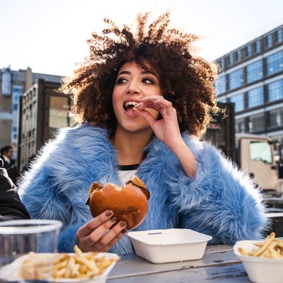 Young couple eating burger and chips outdoors