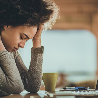 African American woman having a headache from working on a computer at home.