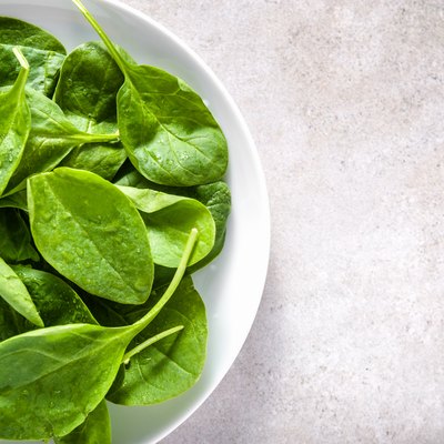 Green vegetables - spinach on plate, healthy food, vegan diet concept.