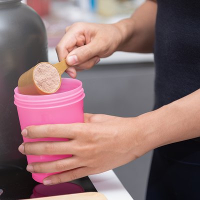 Healthy women preparing a whey protein after doing weight training in the kitchen.