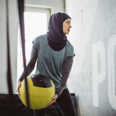 Woman doing HIIT workout with medicine ball at the gym