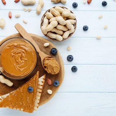 Bread with peanut butter, blueberries and nuts on wooden table