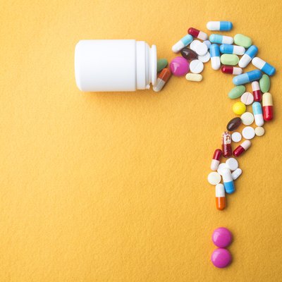 Colorful personalized vitamins spilling out of a white bottle and forming a question mark