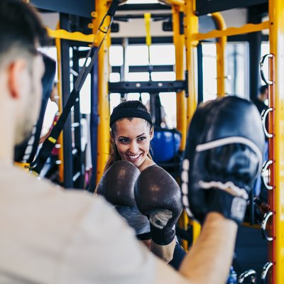 Young woman at boxing training punching in bag