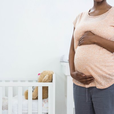 Pregnant woman standing near cradle