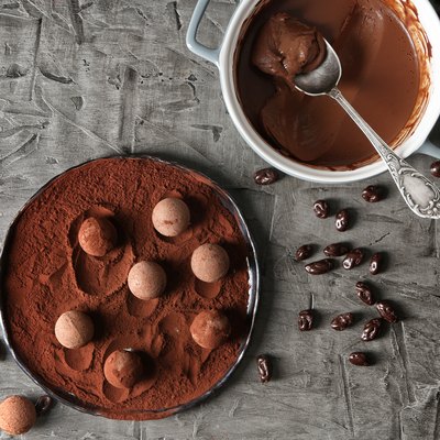 Plate with sweet truffles, ganache and cacao powder on grey table