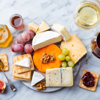 Assortment of cheese, grapes with red and white wine in glasses. Marble background. Top view.
