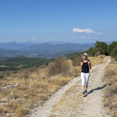 Independent solo traveler woman on the road at Dentelles de Montmirail chain of mountains in Provence in Vaucluse, France