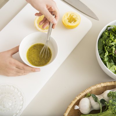 Young woman preparing a fresh salad dressing for how to season food