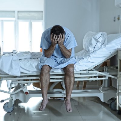desperate sick man at hospital bed alone sad and depressed