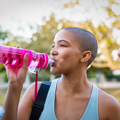 Sporty woman drinking water after exercise