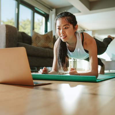 Woman in plank pose following along to a Pilates workout video