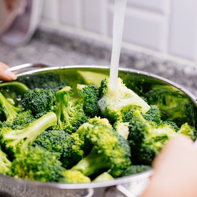 Woman washing broccoli in the kitchen sink