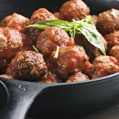 A cast iron pan full of meatballs in tomato sauce