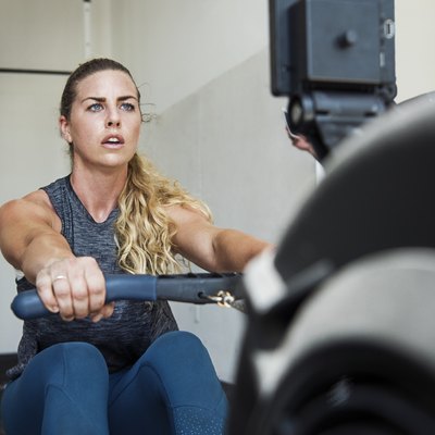 Focused athlete exercising on rowing machine in crossfit gym