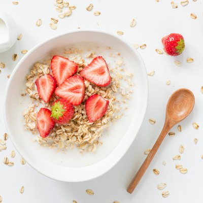 Oatmeal porridge with strawberries and milk in bowl