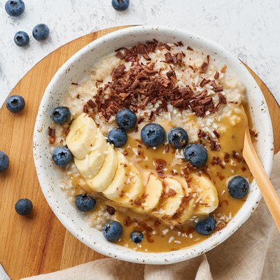 Oatmeal with berries and fruits, dash diet, on wooden white background top view