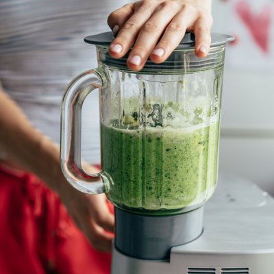 Close view of a woman on the Body Reset Diet blending a green smoothie