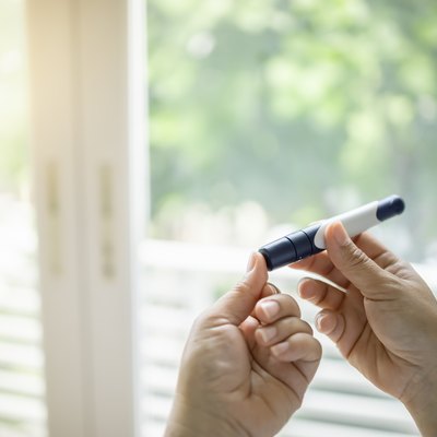 Close up of woman hands using lancet on finger to check blood sugar levels