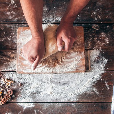 Hands kneading raw dough on table flat lay