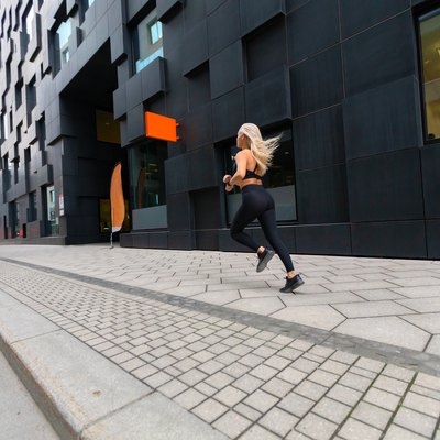 Back view of a fast running fit woman in modern city environment