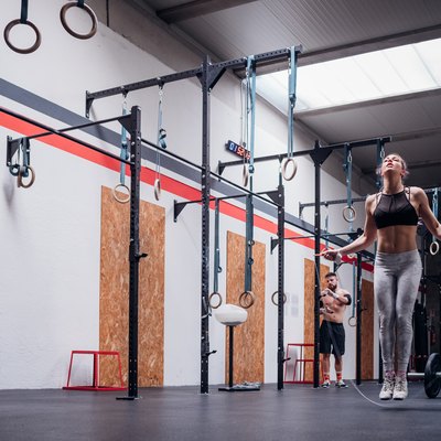 Young woman training, skipping in gym, full length