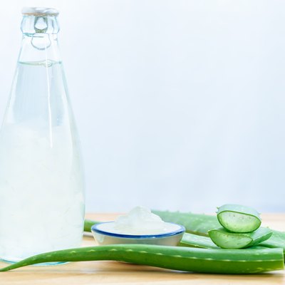Fresh aloe vera leaves with aloe vera juice in bottle on wooden