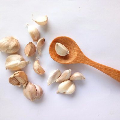 Close-Up Of Garlic With Wooden Spoon Over White Background