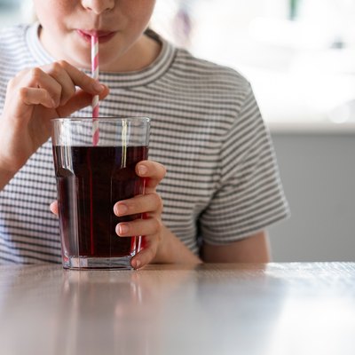 Close Up Of Girl Drinking Sugary Fizzy Soda From Glass With Straw
