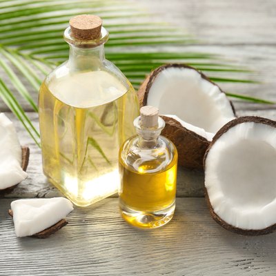 Bottles with fresh coconut oil palmitic acid on wooden table