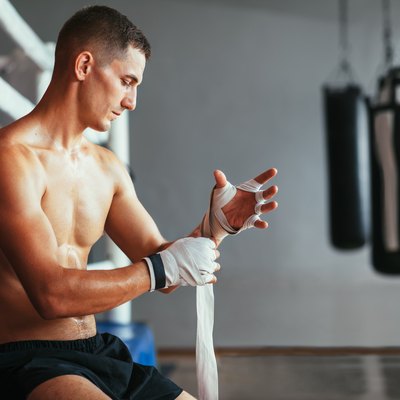 Male boxer is wrapping hands with boxing wraps