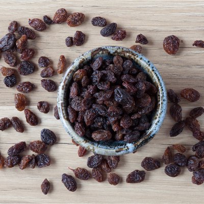 Organic raisins in bowl on wood