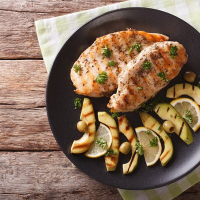 Grilled turkey breast with avocado, lemon and olive close-up. horizontal top view