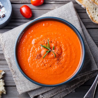 Tomato cold soup recipes in a black bowl on wooden background. Top view. Copy space