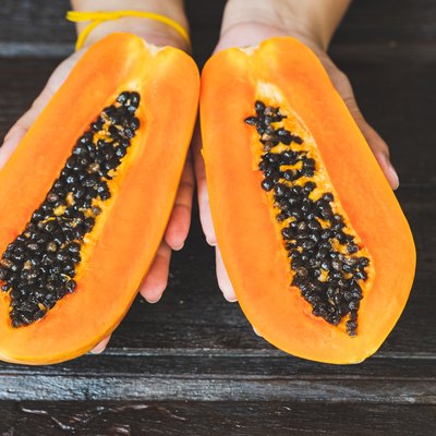Cropped Hand Of Woman Holding Halved Papayas