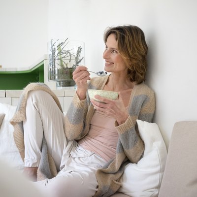 Relaxed smiling mature woman sitting on bench eating healthy food