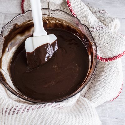 A bowl of chocolate brownie ingredients being stirred by a spatula.