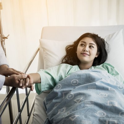 Medical doctor talking to patient and Holding her hand to comforting her. Female patient having injury lying on bed at hospital.