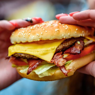 Woman hand is holding a fresh burger before eating on street