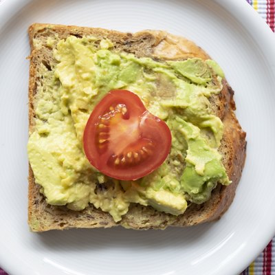 Whole-wheat toast with avocado and tomato on a white plate to lower blood sugar at night