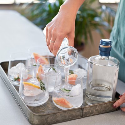 Anonymous woman's hands pouring drinks into glasses in a drinks tray