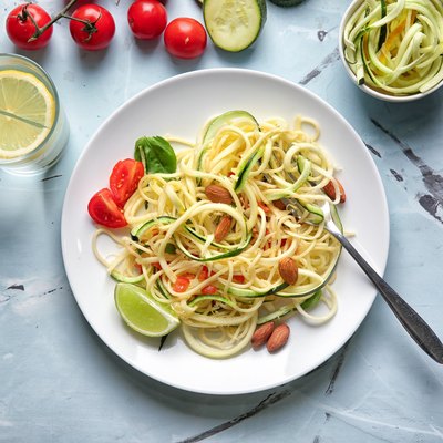 Plate of spaghetti with zucchini on table