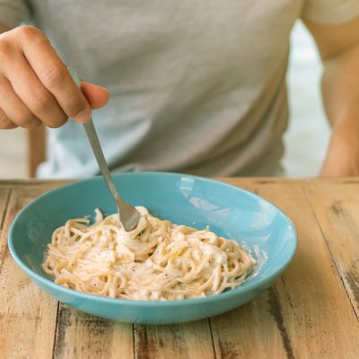 Men eating spaghetti with creamy cheese sauce.