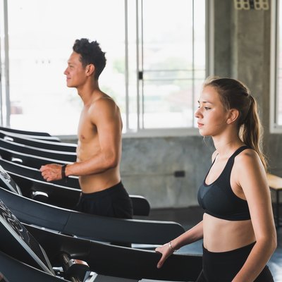 Young couple exercising by running on the treadmill to maintain good health