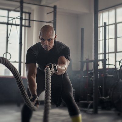 Mature strong man doing battle rope exercises during a CrossFit MetCon workout
