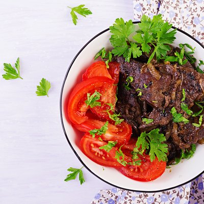 Roasted or grilled beef liver with onion and tomatoes salad. Middle Eastern cuisine. Top view