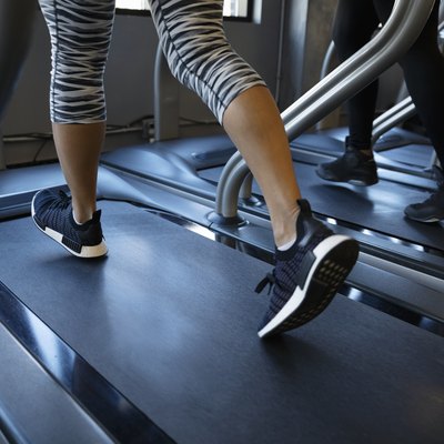 Legs of woman walking on treadmill in gym