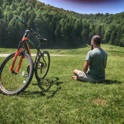 Man practicing yoga for cyclists next to his bike outdoors