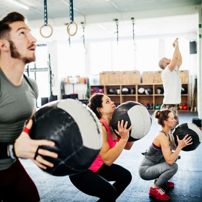 People doing an EMOM workout with medicine balls at a CrossFit box