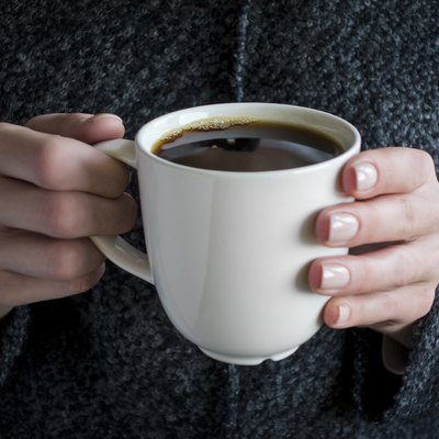 holding a cup of black coffee